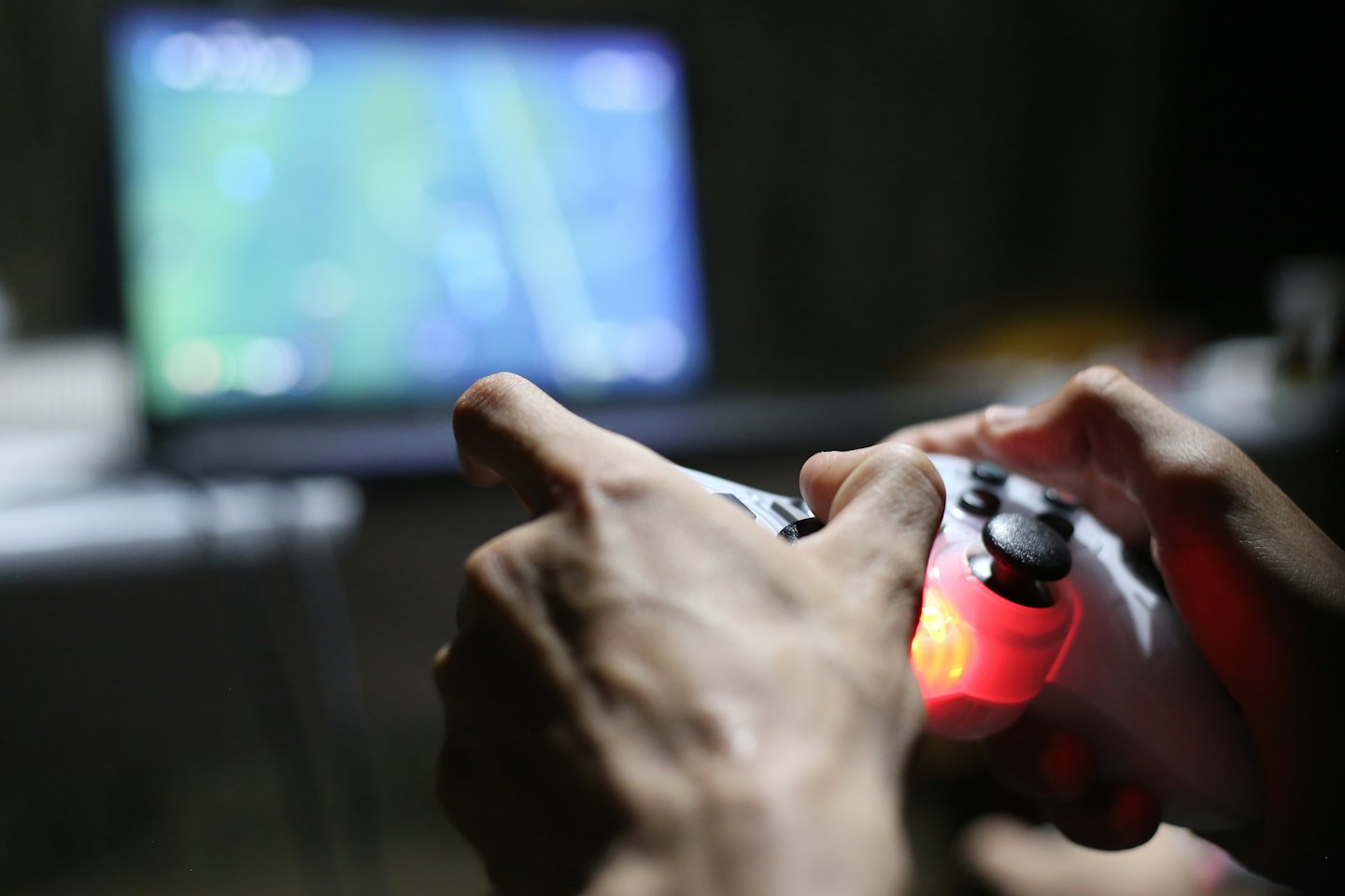 Mains tenant une manette de jeu vidéo avec une lumière rougeoyante.